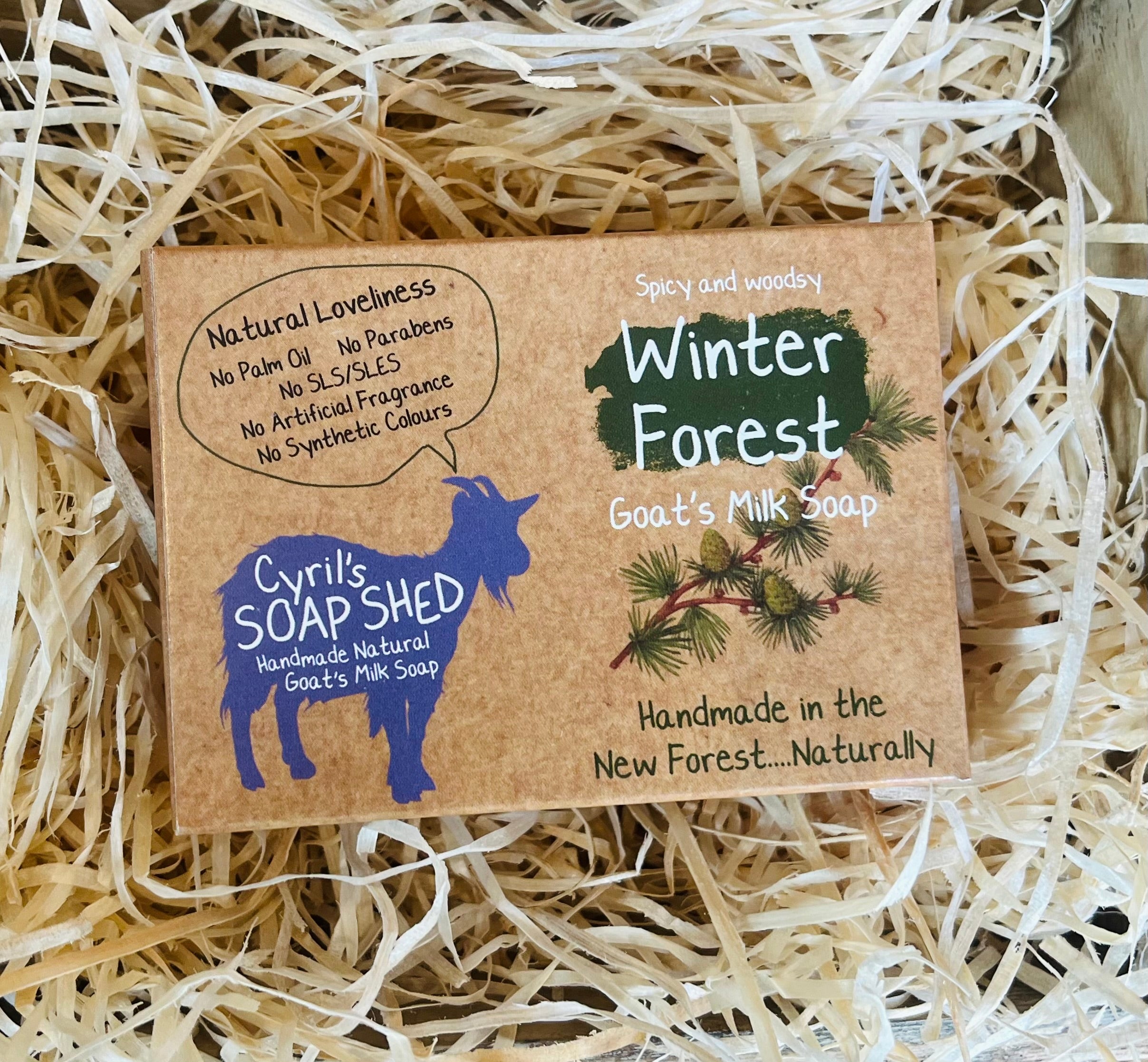 Goat's milk soap packaging with 'Winter Forest' design on a bed of straw.