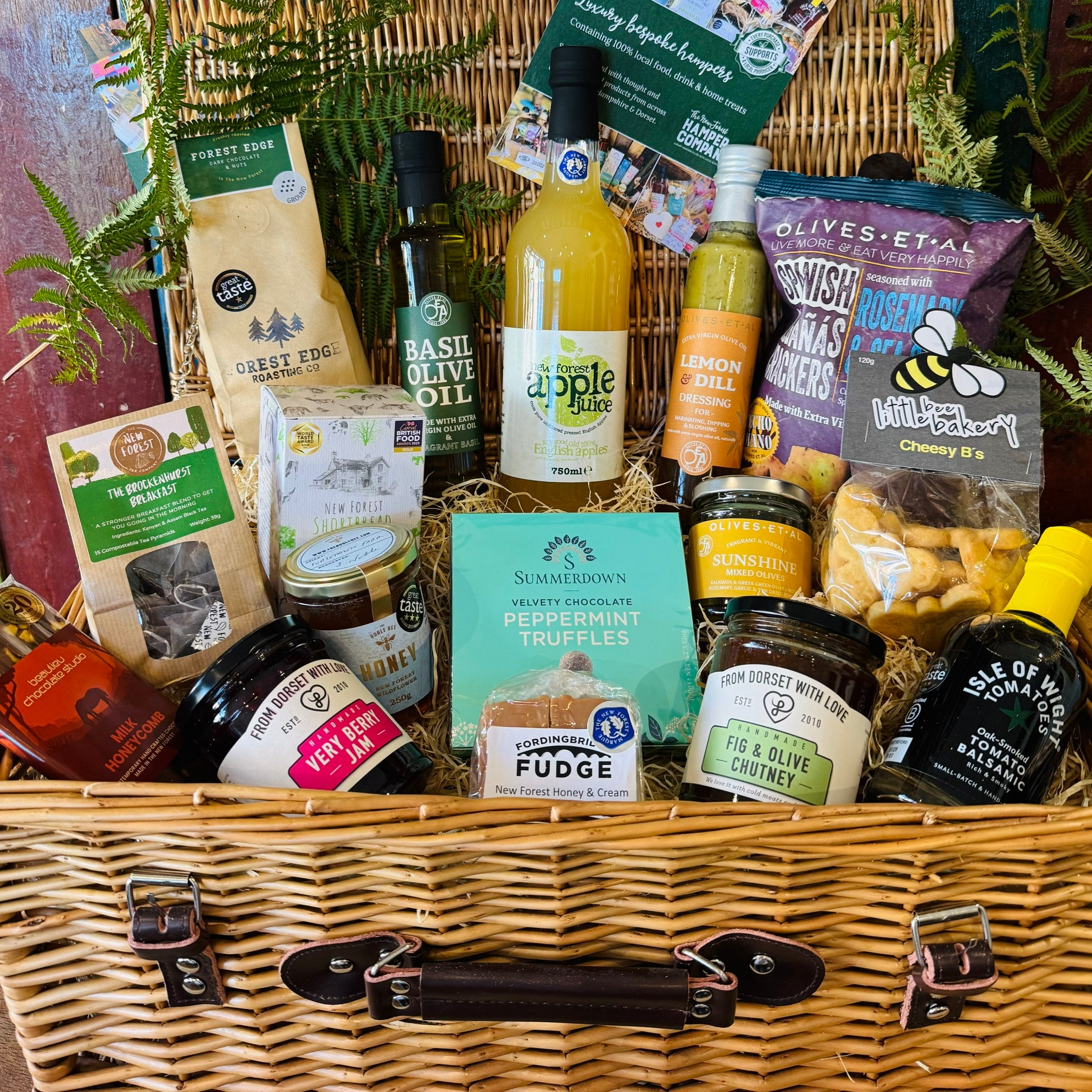 The Local Pantry Hamper - a 20 inch lidded willow basket of New Forest food and drink with no alcohol, holding Olives et Al crackers and olives, Basil olive oil, New Forest apple juice, Forest Edge coffee, Summerdown peppermint truffles and New Forest wildflower honey