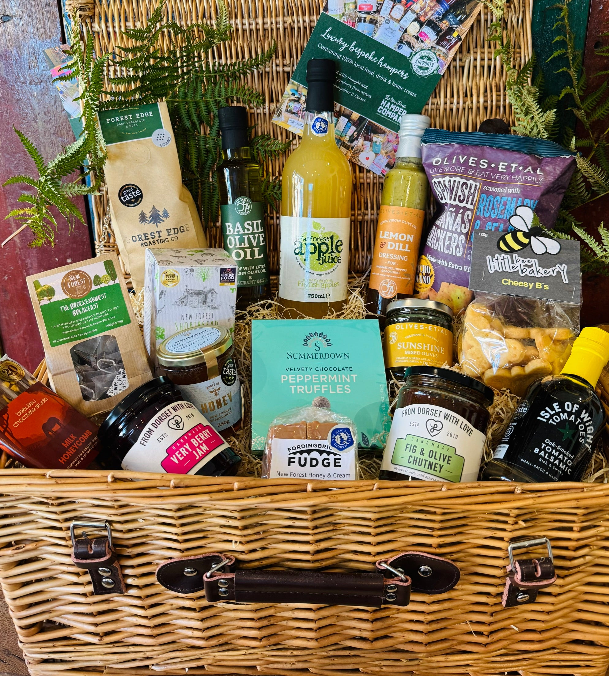 The Local Pantry Hamper - a 20 inch lidded willow basket of New Forest food and drink with no alcohol, holding Olives et Al crackers and olives, Basil olive oil, New Forest apple juice, Forest Edge coffee, Summerdown peppermint truffles and New Forest wildflower honey