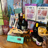 The Indulgent Wine, Cheese & Charcuterie Hamper laid out - two wines, Dorset charcuterie, Lyburn cheeses, olives, oils, chutneys and Summerdown peppermint crisps