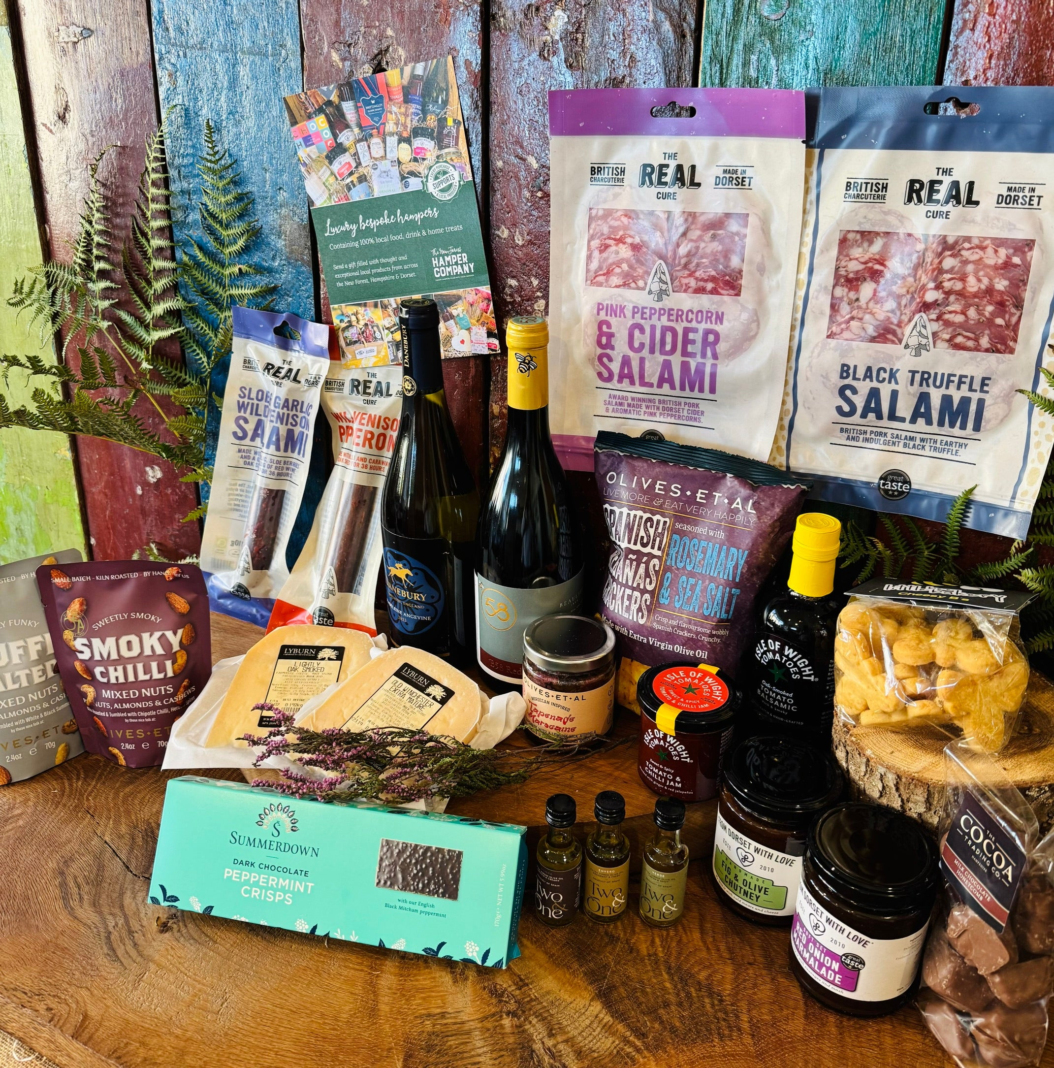 The Indulgent Wine, Cheese & Charcuterie Hamper laid out - two wines, Dorset charcuterie, Lyburn cheeses, olives, oils, chutneys and Summerdown peppermint crisps