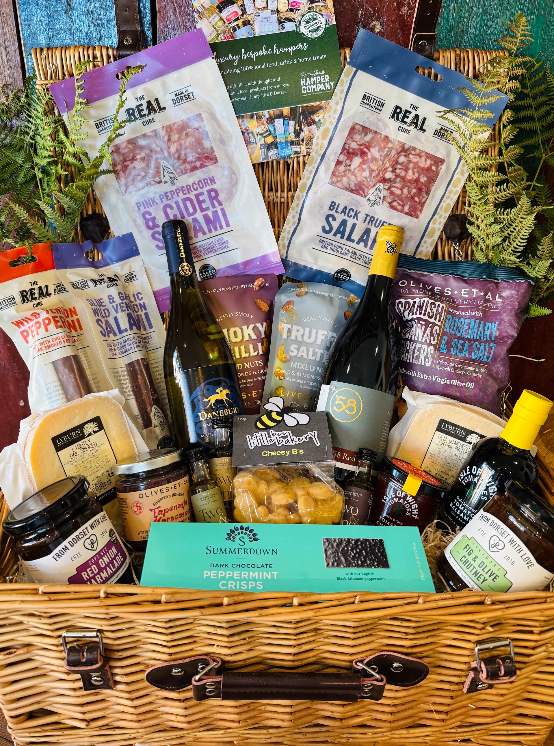 The Indulgent Wine, Cheese & Charcuterie Hamper - a 20 inch lidded willow basket with B58 Red and Danebury white wine, four Real Cure Dorset salamis, two Lyburn cheeses, olives, crackers and chutneys