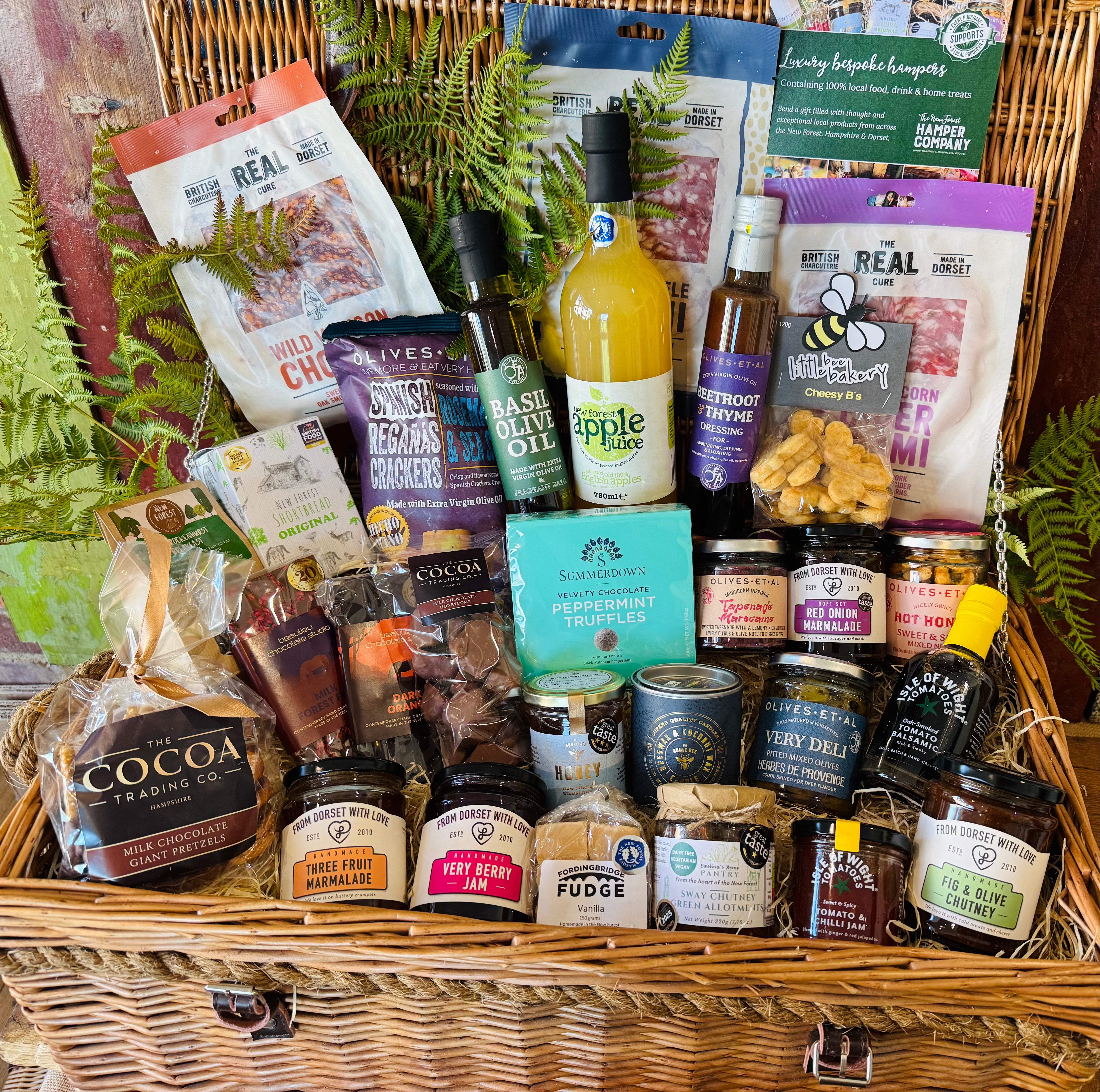 Close view of The Ultimate Hampshire & Dorset Goodies Hamper showing red onion marmalade, Sway Chutney, fig and olive chutney, Herbes de Provence olives, oak-smoked tomato balsamic and New Forest wildflower honey