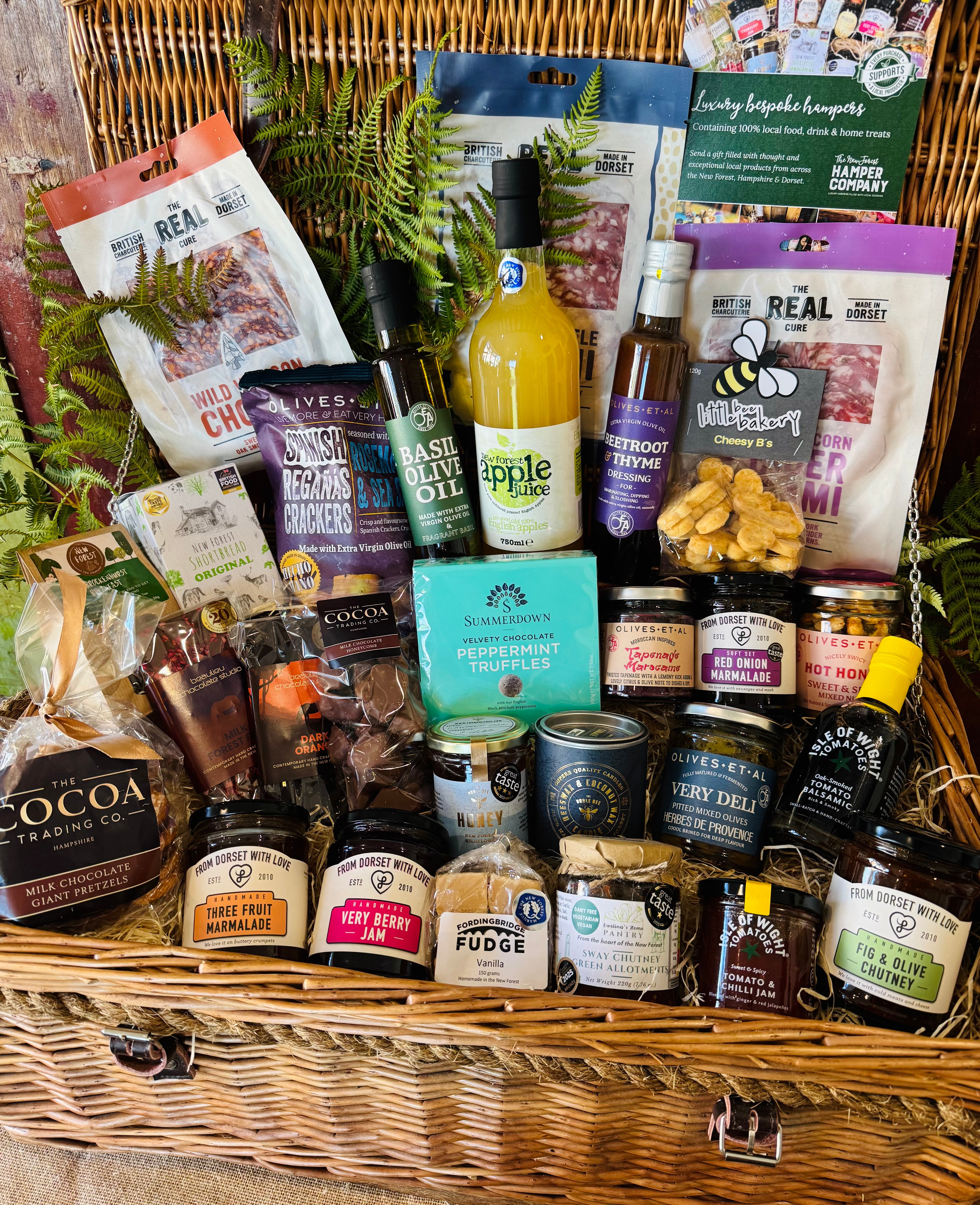 The Ultimate Hampshire & Dorset Goodies Hamper from above - twenty-nine items including Summerdown peppermint truffles, chocolate dipped giant pretzels, New Forest Shortbread and Brockenhurst Breakfast tea in a 24 inch willow basket