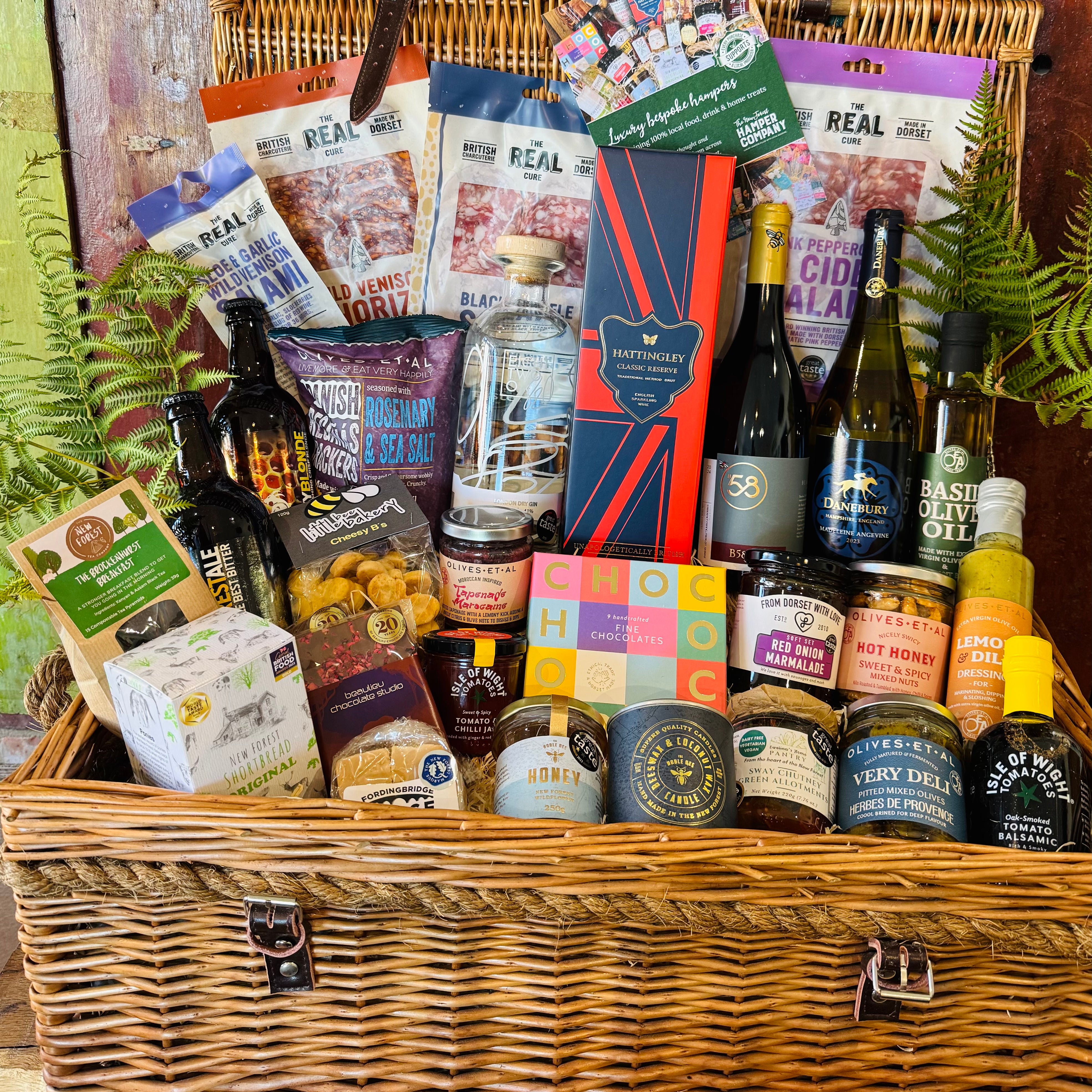 The Ultimate Hampshire & Dorset Hamper - a 24 inch lidded willow basket filled with Hattingley Valley sparkling wine, B58 and Danebury wines, 820 Spirits gin, Downton ales, Real Cure charcuterie, Chococo chocolates and local preserves, dressed with fern