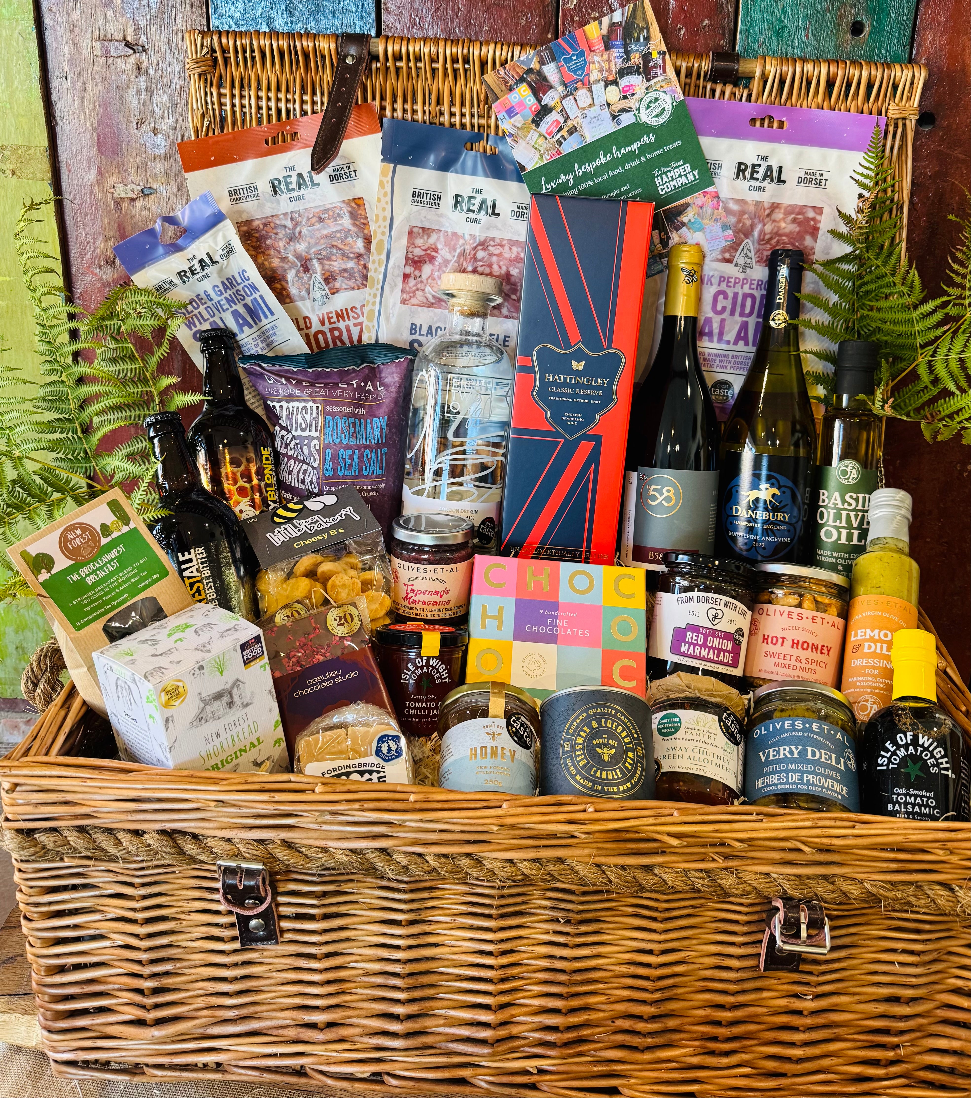 The Ultimate Hampshire & Dorset Hamper - a 24 inch lidded willow basket filled with Hattingley Valley sparkling wine, B58 and Danebury wines, 820 Spirits gin, Downton ales, Real Cure charcuterie, Chococo chocolates and local preserves, dressed with fern
