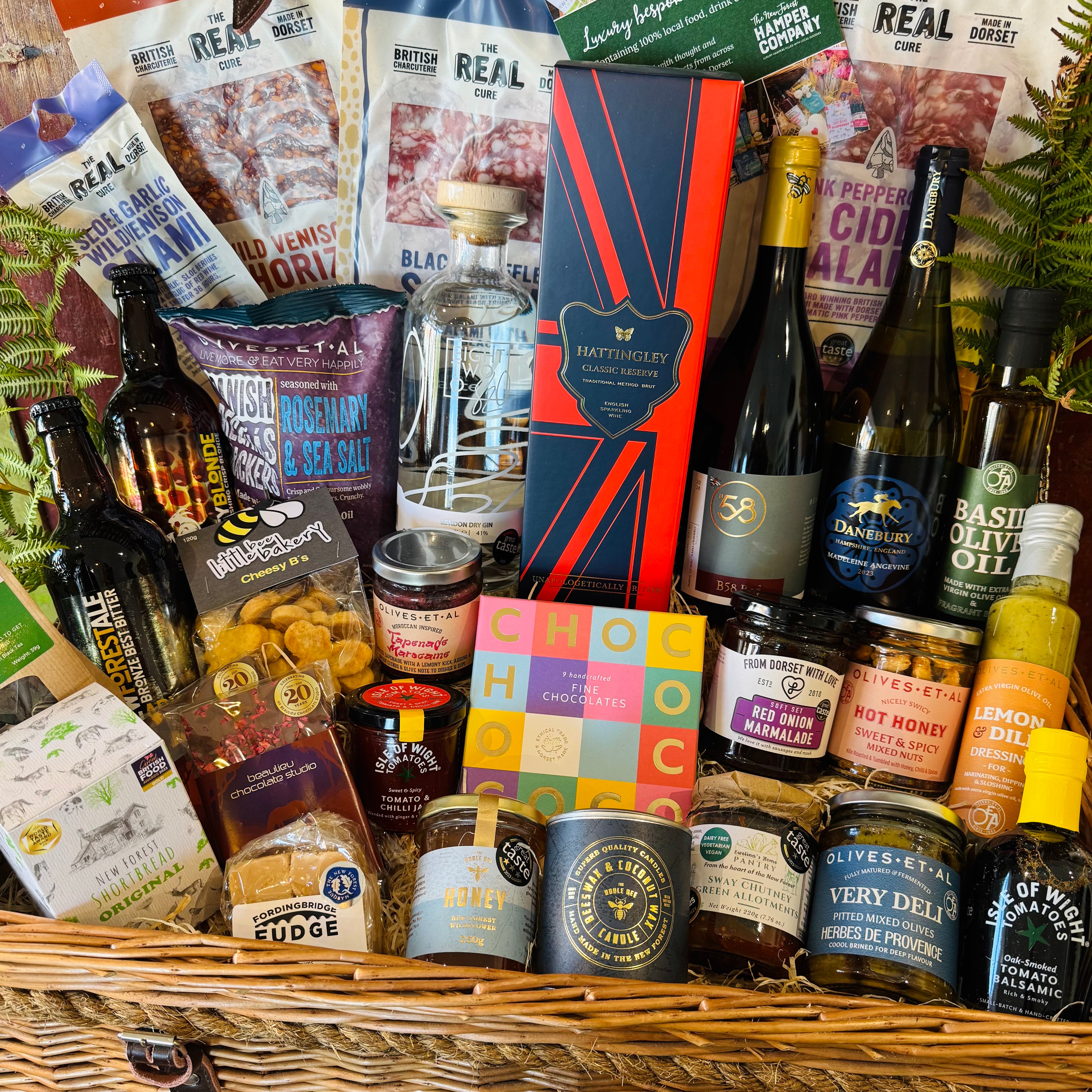 Close view of The Ultimate Hampshire & Dorset Hamper showing Chococo handcrafted chocolates, red onion marmalade, hot honey nuts, Sway Chutney, Herbes de Provence olives, New Forest wildflower honey and a Noble Bee beeswax candle