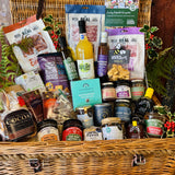 The Ultimate Christmas Goodies Hamper - a 24 inch lidded willow basket filled with Real Cure charcuterie, Cheesy Stars, festive preserves, chocolates, mince pie fudge, New Forest apple juice and a Christmas spice candle, dressed with holly and fern