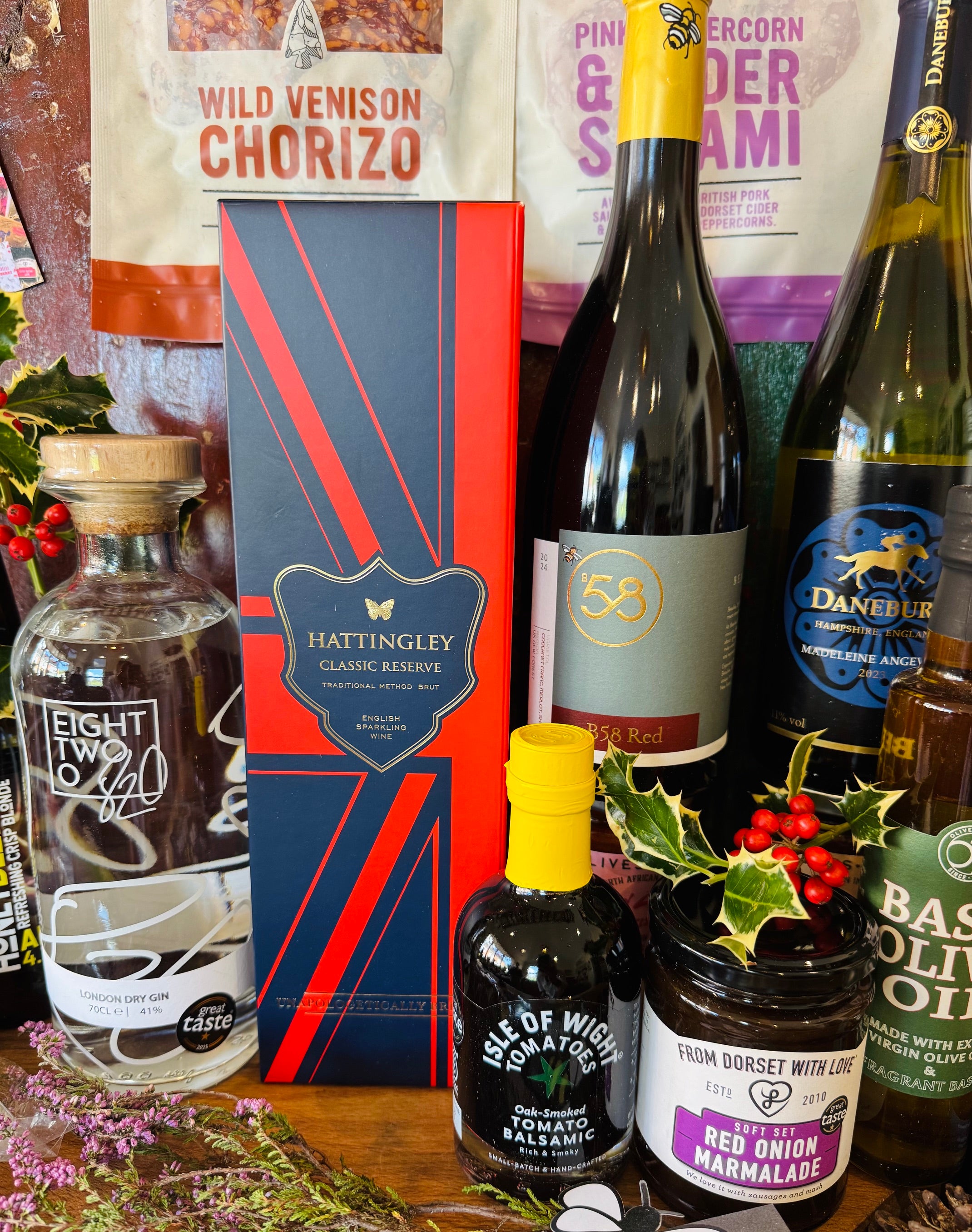 Thirty-item display of The Ultimate Hampshire & Dorset Christmas Hamper - English sparkling wine, red and white wine, New Forest gin, two local ales, Real Cure charcuterie, cheese biscuits and Spanish crackers, olives, tapenade, festive preserves, chocolates and a candle