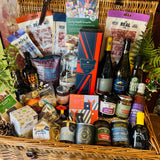 Close view of The Ultimate Hampshire & Dorset Christmas Hamper showing the Chococo Festive Collection, Christmas chutney, Christmas pudding festive nuts, red onion marmalade, mince pie fudge and a Noble Bee Christmas spice candle