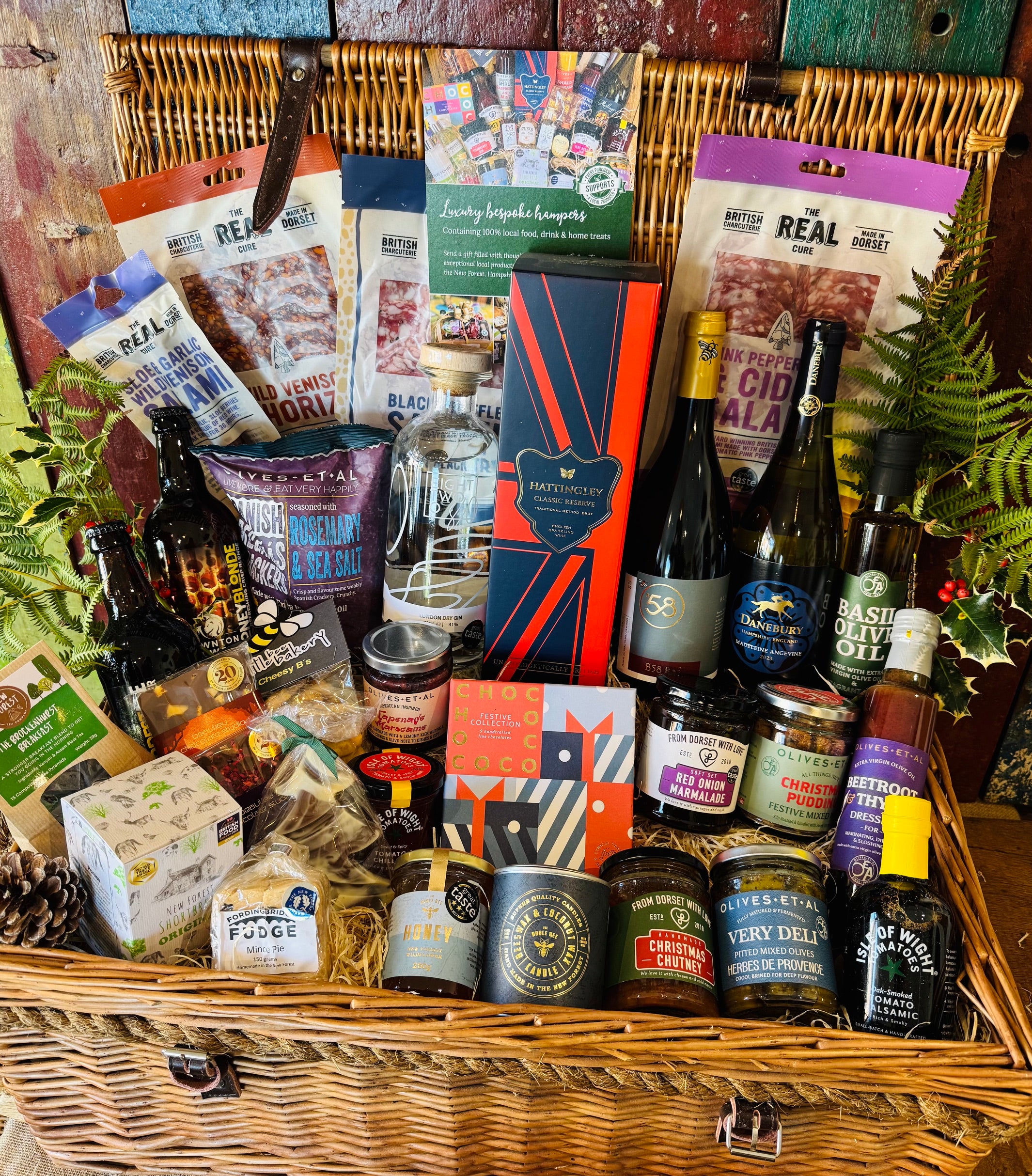 Close view of The Ultimate Hampshire & Dorset Christmas Hamper showing the Chococo Festive Collection, Christmas chutney, Christmas pudding festive nuts, red onion marmalade, mince pie fudge and a Noble Bee Christmas spice candle