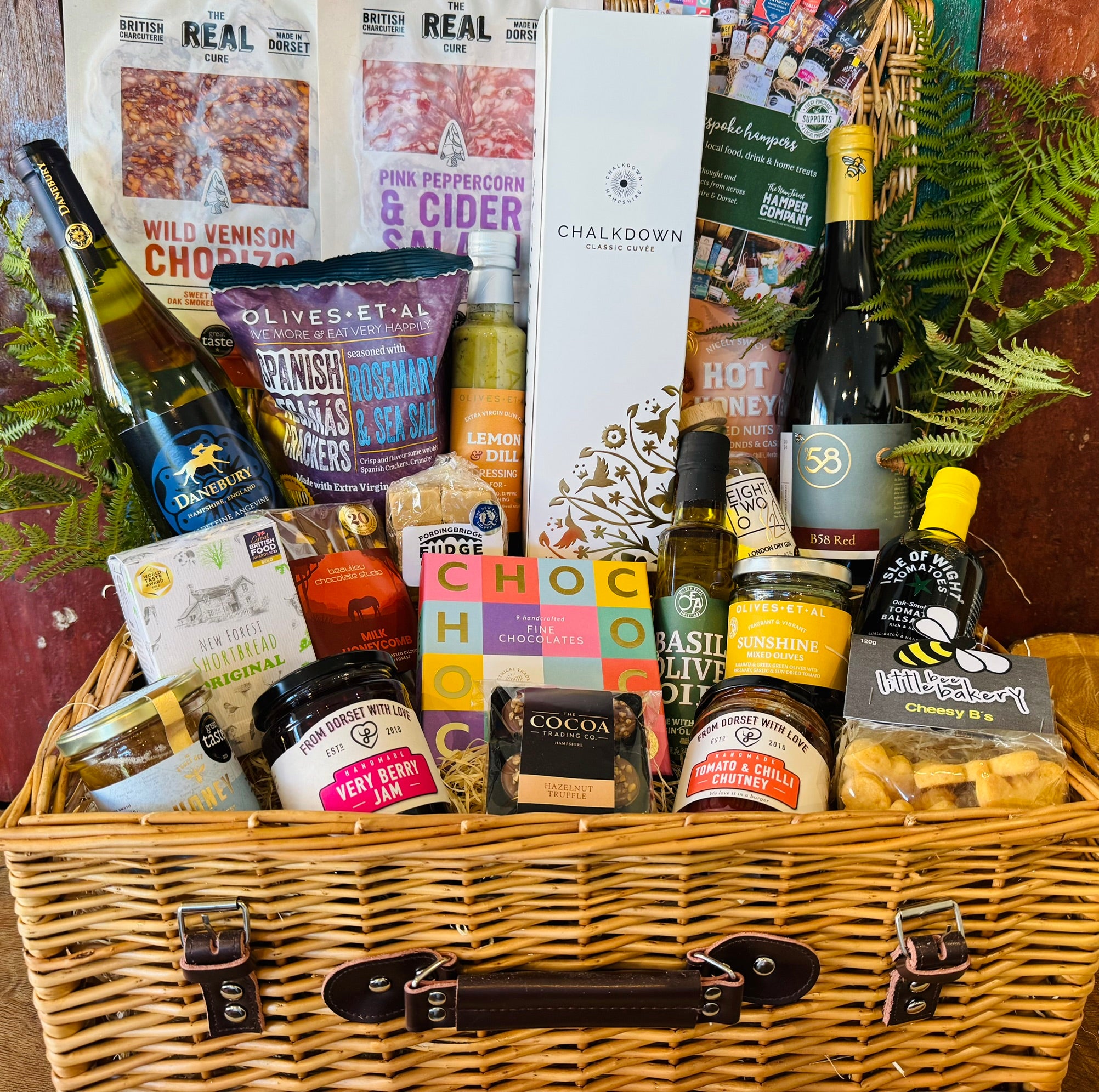 The Indulgent Celebration Hamper - a 20 inch lidded willow basket with Chalkdown sparkling, Danebury and B58 wines, 820 Spirits gin, Dorset charcuterie, chocolates and New Forest preserves