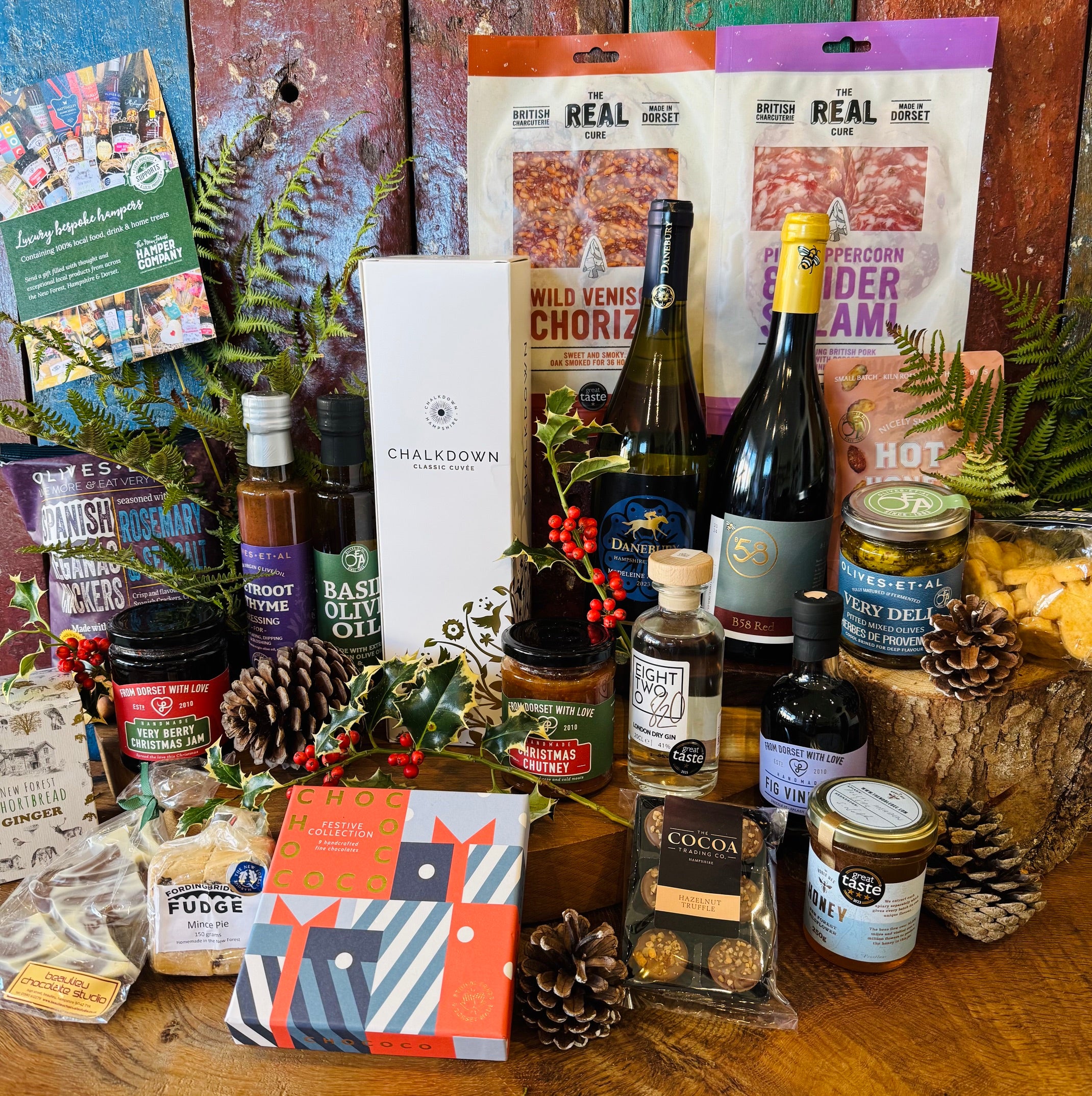 Everything in the Chalkdown Fizz & Festive Goodies Hamper laid out: four bottles, Dorset salami, preserves and Christmas chocolates
