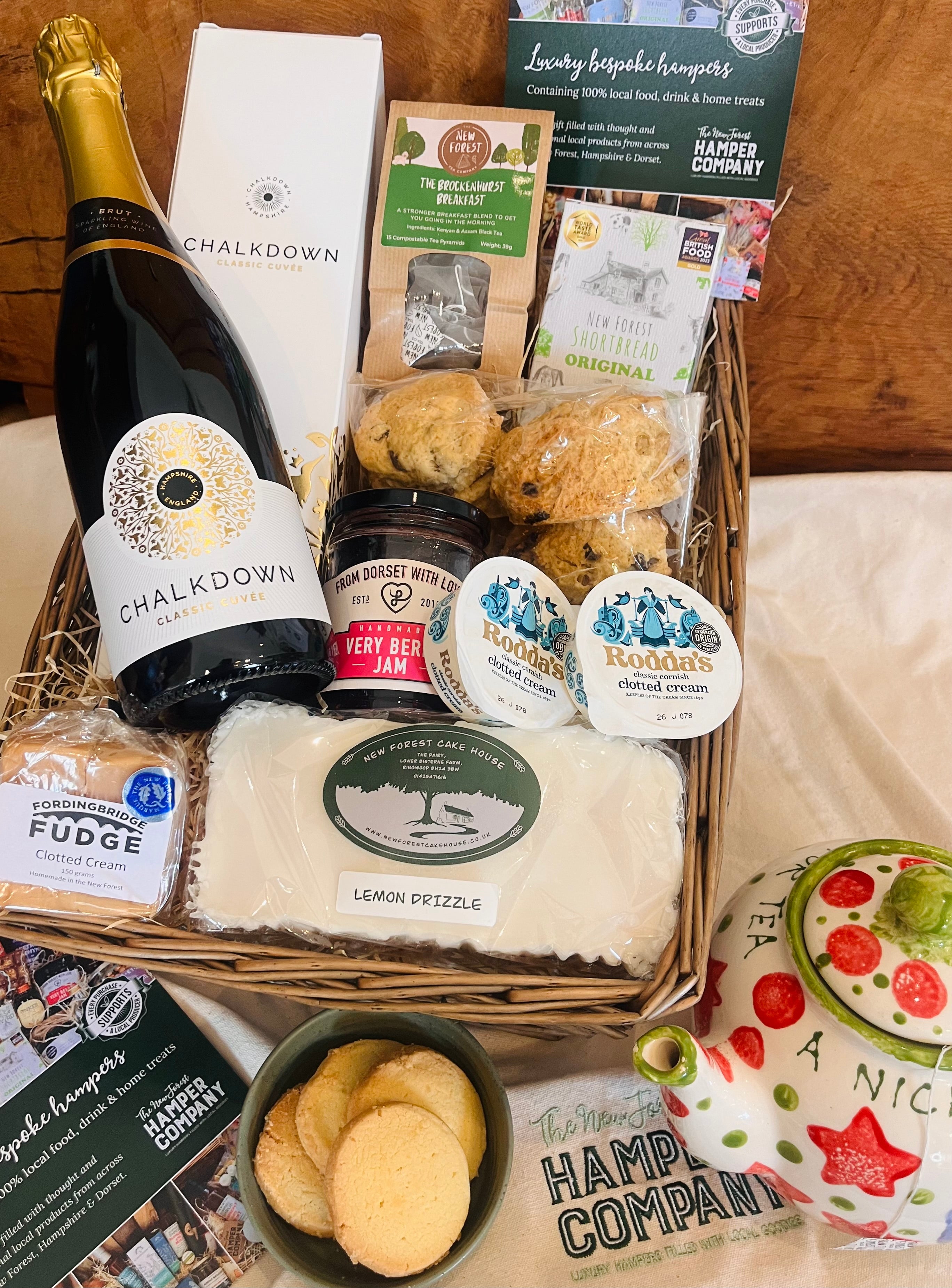 Chalkdown Afternoon Tea Hamper contents laid out with Chalkdown Classic Cuvée, The Forest Deli fruit scones, Rodda's Cornish clotted cream and New Forest Cake House lemon drizzle