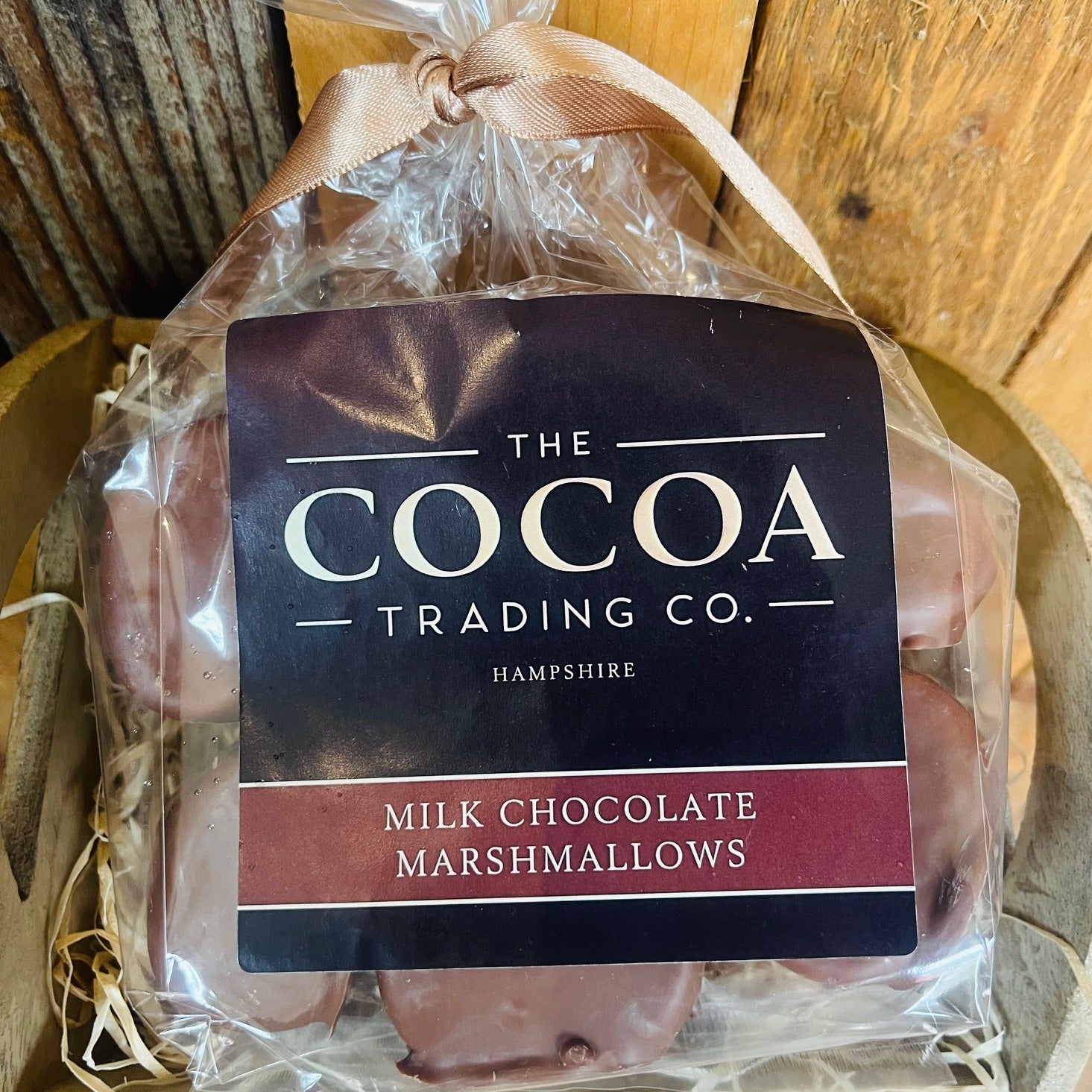 Packaged milk chocolate marshmallows from The Cocoa Trading Co. on a wooden surface.
