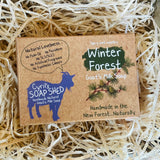 Goat's milk soap packaging with 'Winter Forest' design on a bed of straw.