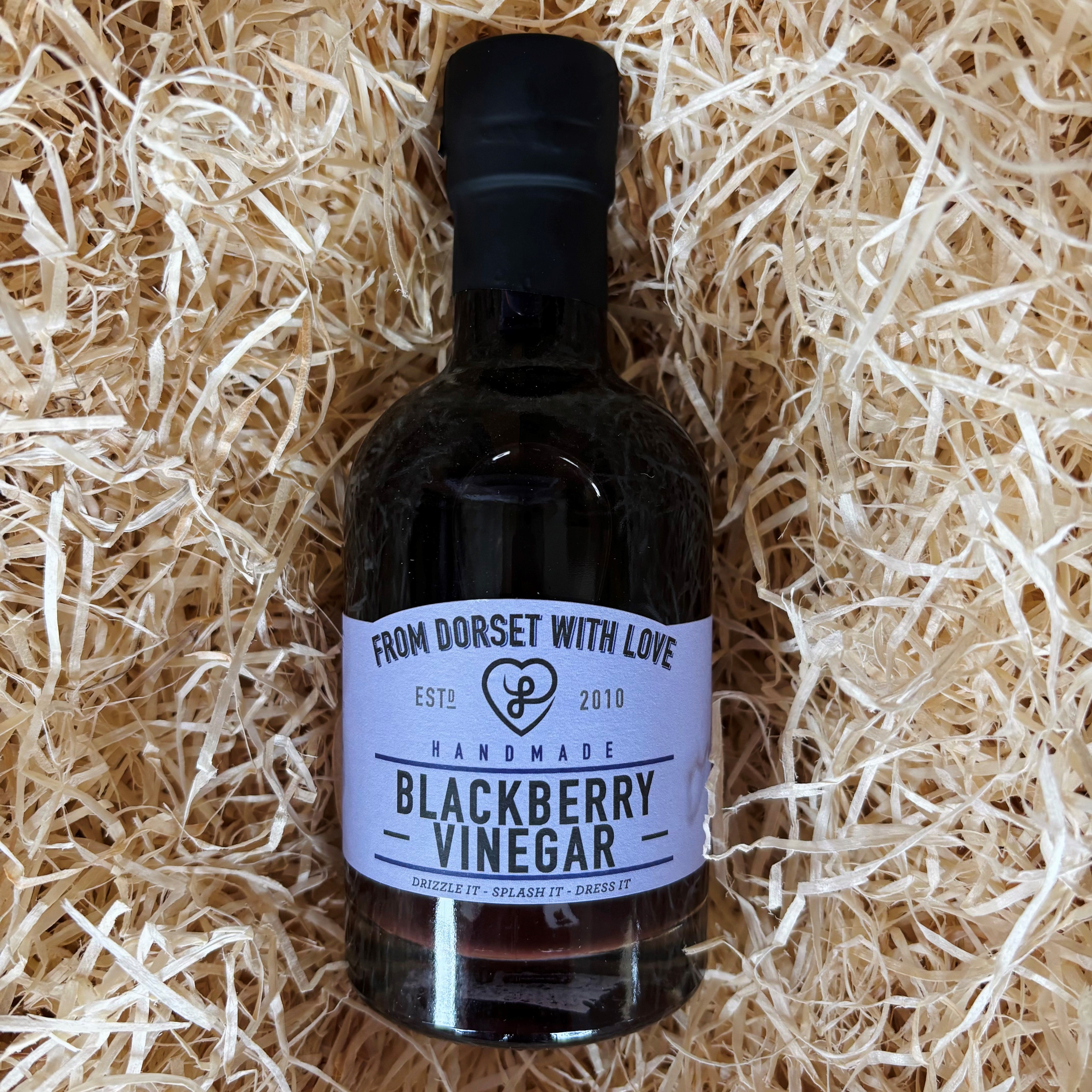 Bottle of blackberry vinegar with a label on a bed of straw