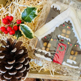 Little Bee Bakery hand-iced Christmas House biscuit, a snow-topped cottage with a red door and a garland of fairy lights, in a wooden gift crate with holly, red berries and a pinecone