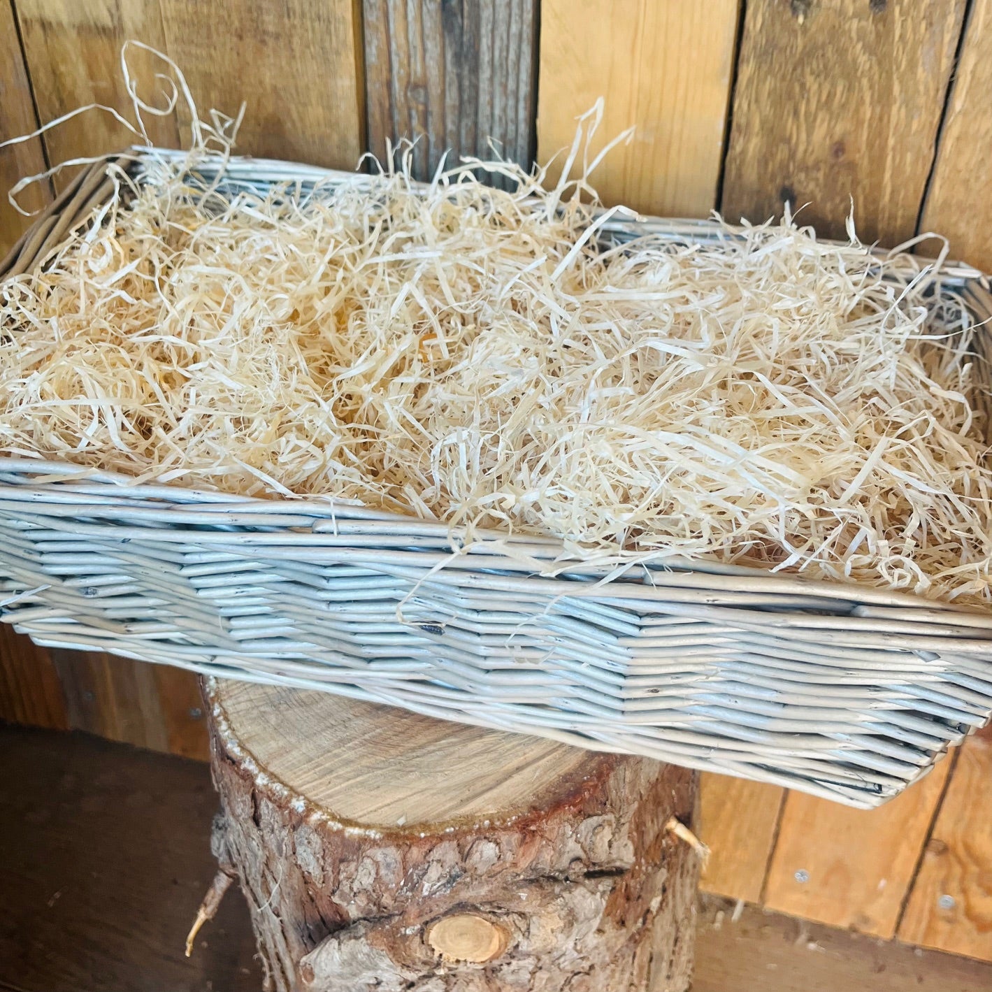 Wicker basket filled with straw on a wooden surface