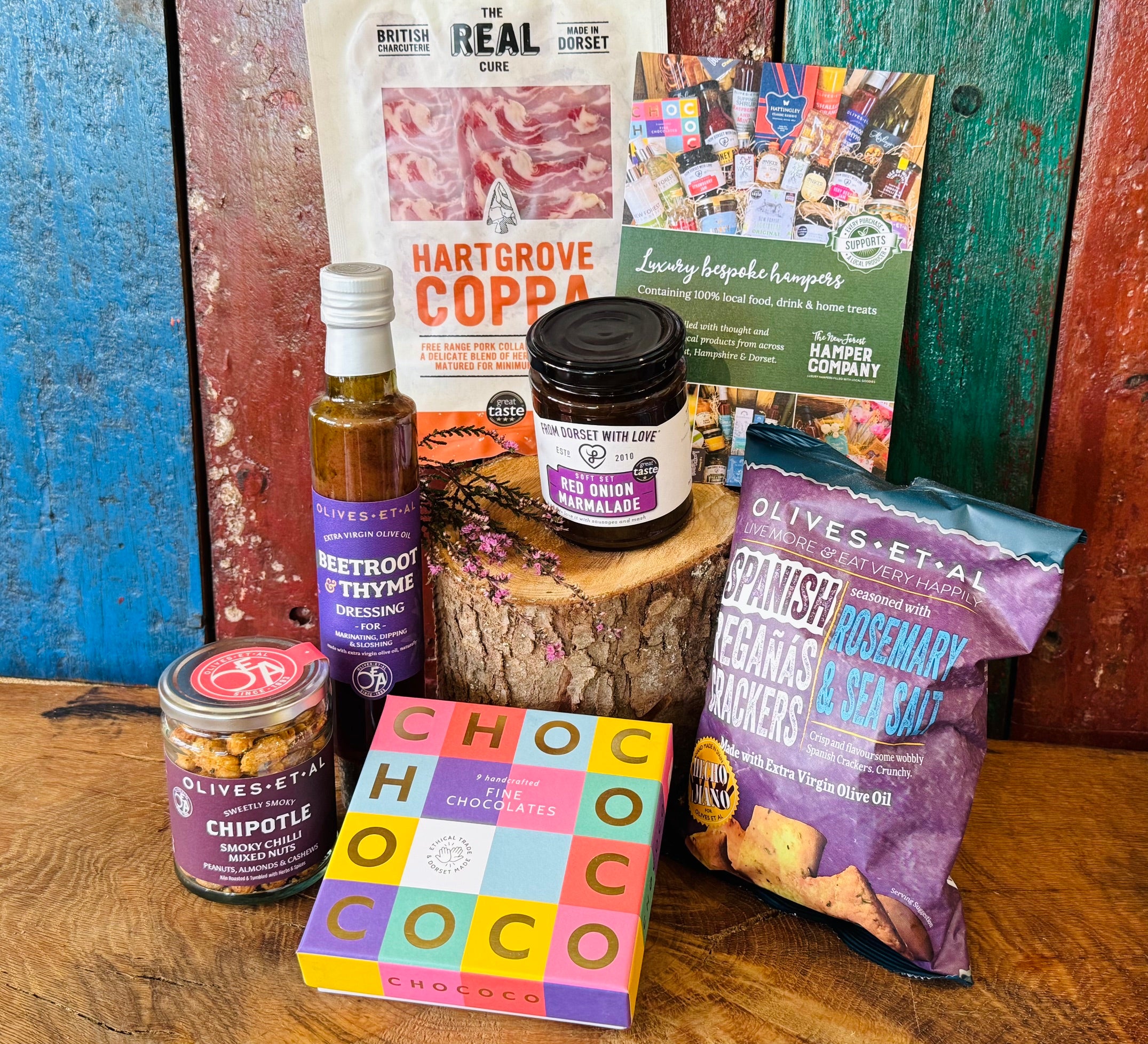 Dorset Giftbox contents laid out with Real Cure Hartgrove Coppa, Chococo handcrafted chocolates, Olives et Al Reganas crackers and Dorset preserves