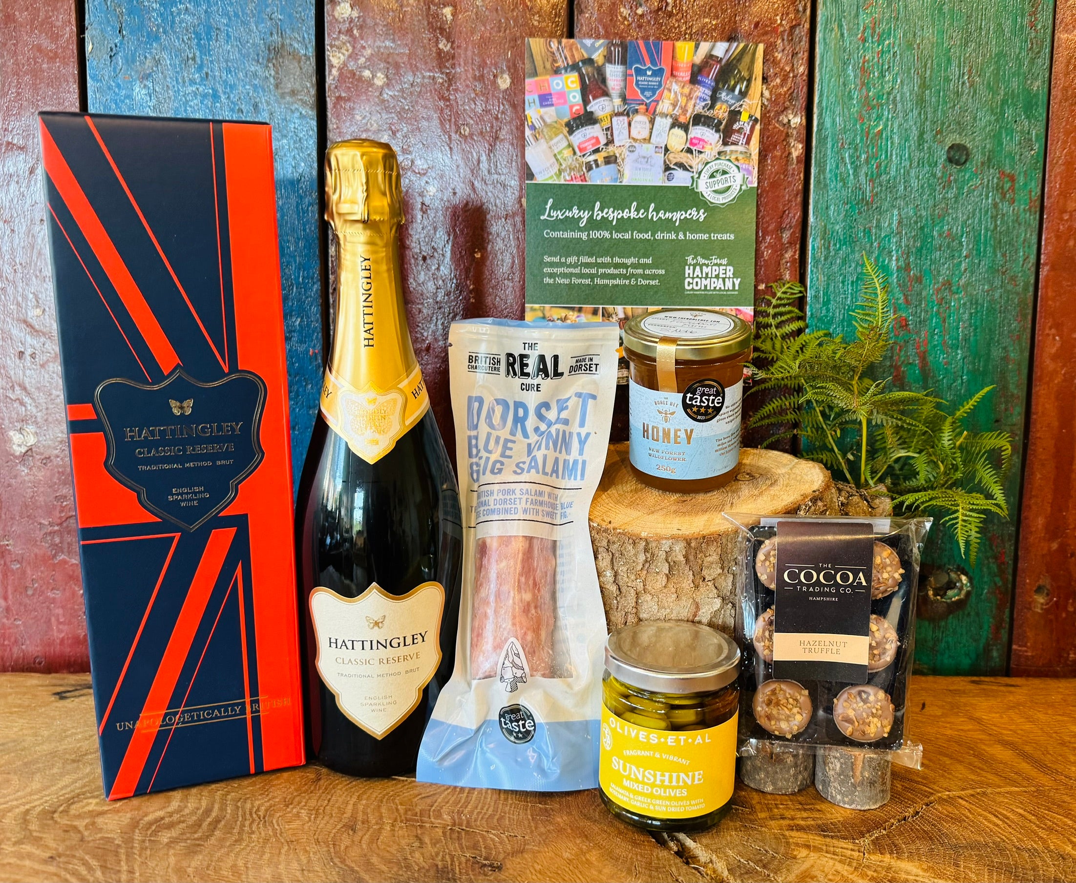 Hattingley Gourmet Grazer contents displayed on wood with English sparkling wine, Dorset Blue Vinny & Fig salami, New Forest wildflower honey and Sunshine mixed olives