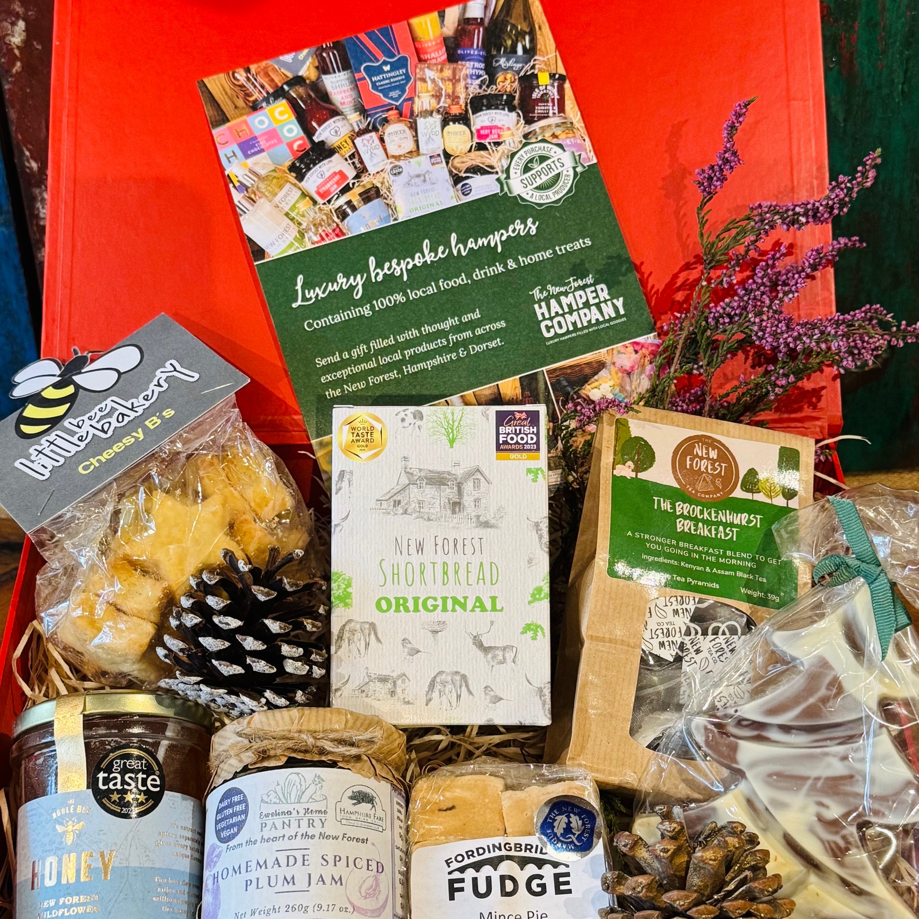 New Forest Festive Favourites Giftbox, a red gift box packed with shortbread, wildflower honey, cheesy stars, mince pie fudge, spiced plum jam, Brockenhurst Breakfast tea and a Beaulieu chocolate Christmas tree