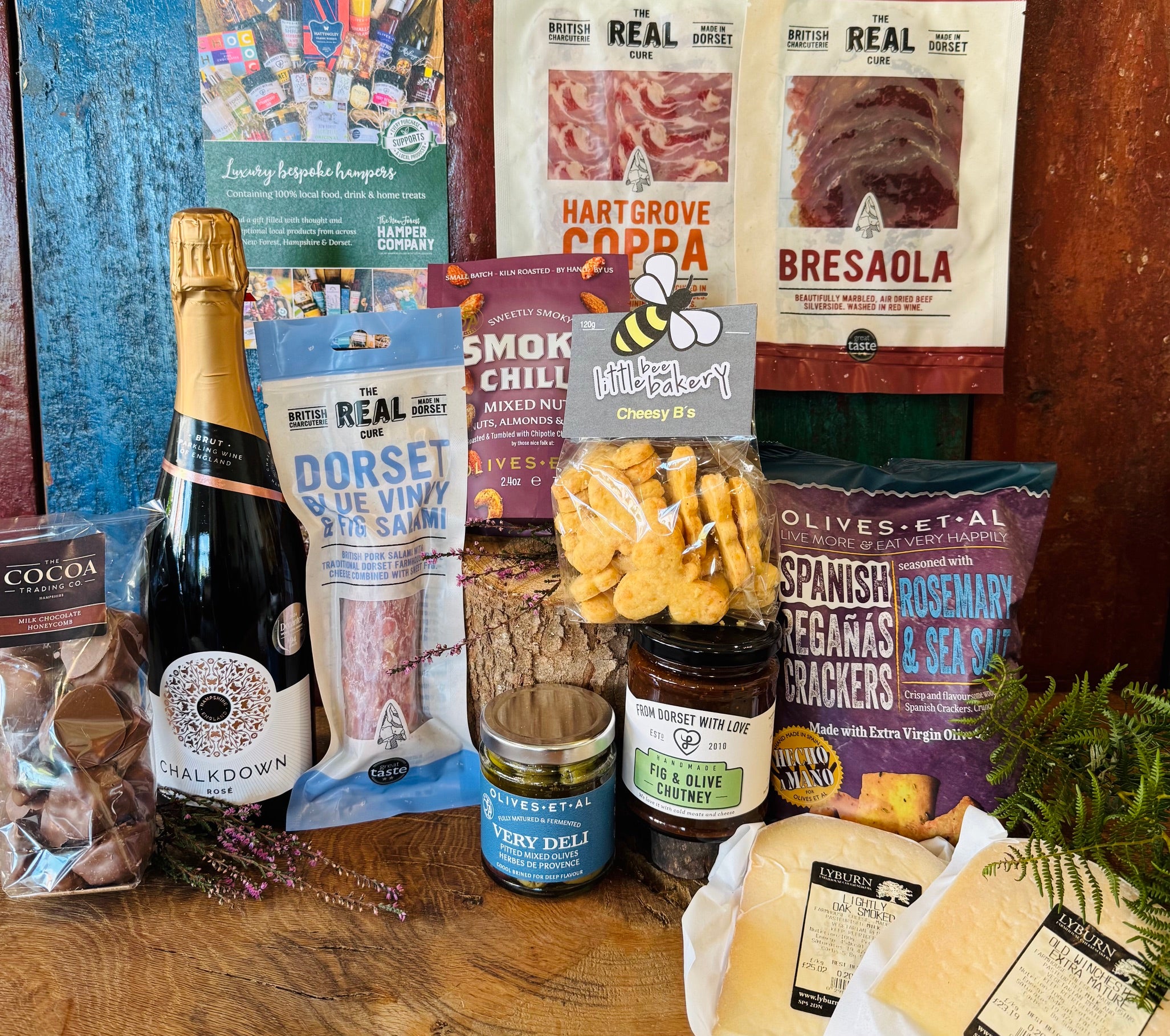 The Perfect Evening In Hamper contents laid out with Chalkdown rose, Real Cure coppa, bresaola and Blue Vinny salami, Lyburn cheeses, Reganas crackers and smoky chilli nuts