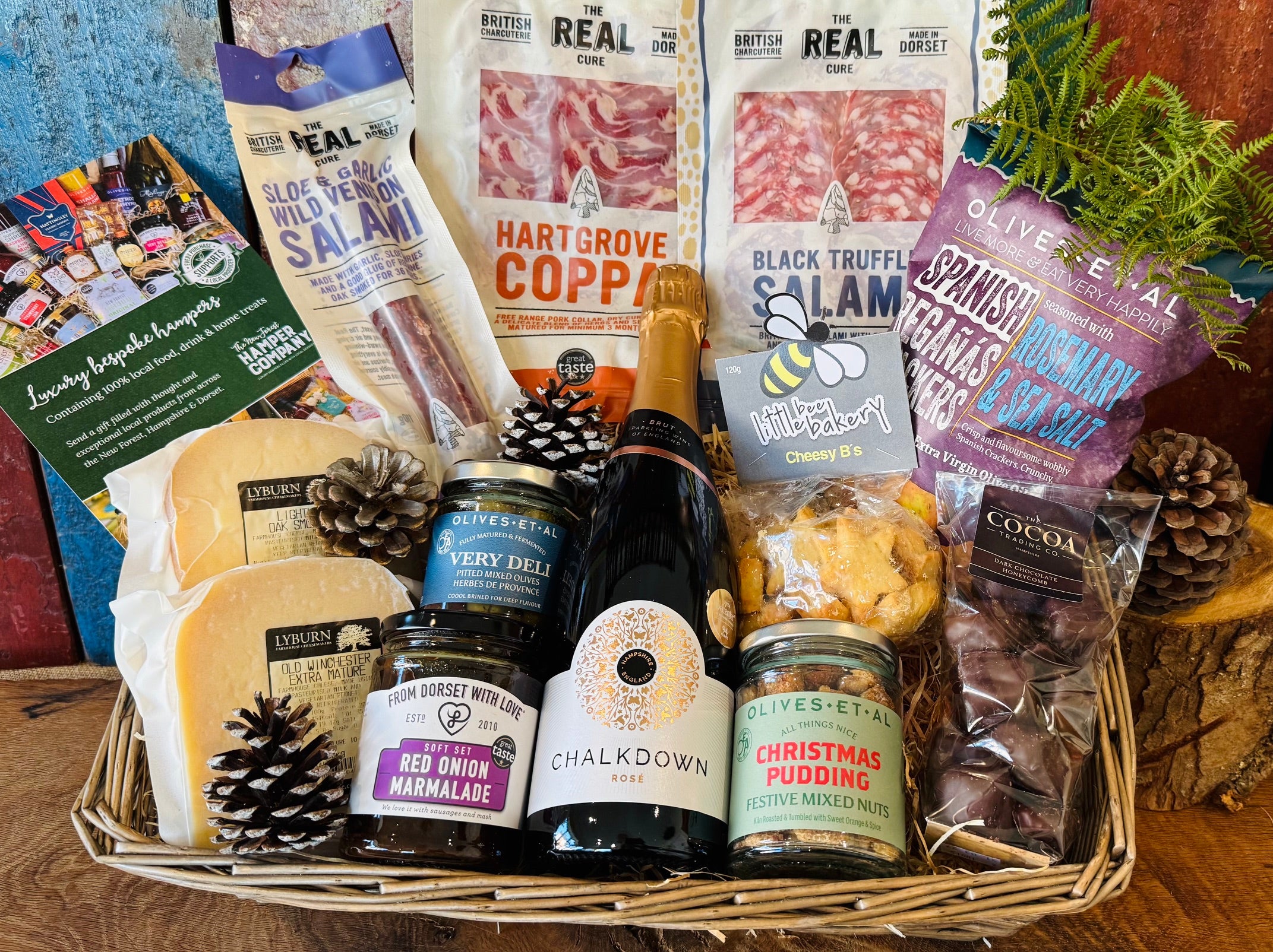 Festive hamper basket styled with pine cones, Hartgrove coppa, black truffle salami, wild venison salami, Lyburn cheeses, red onion marmalade and Cheesy Stars