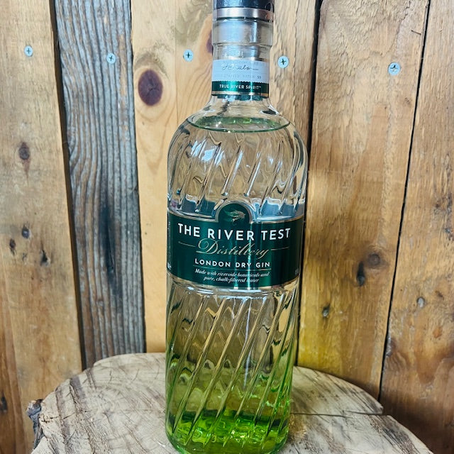Bottle of The River Test Distillery London Dry Gin on a wooden surface with a wooden background
