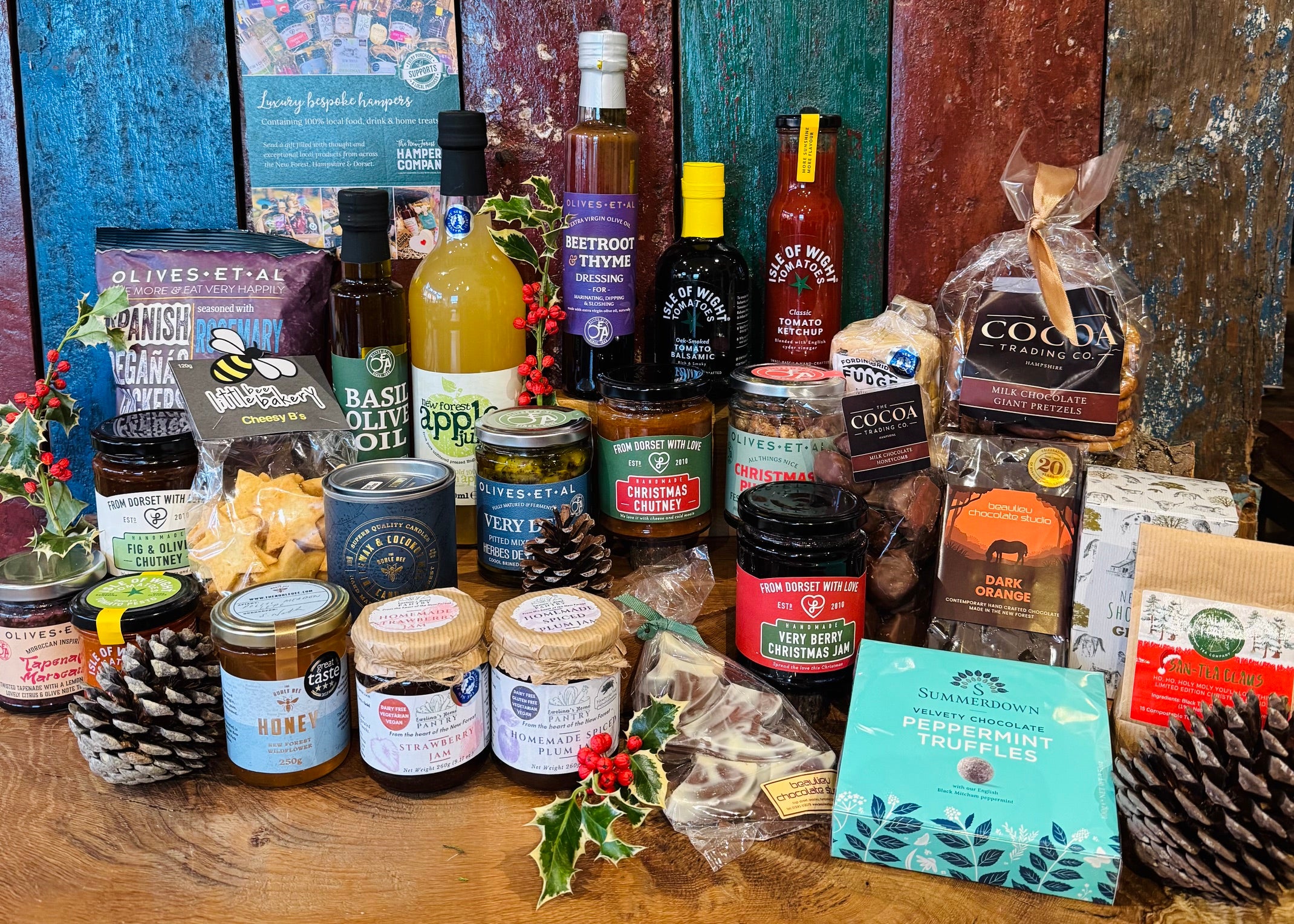 The Ultimate Christmas Goodies Hamper in display format - the full twenty-eight item alcohol-free spread arranged in and around the 24 inch double steamed willow basket with leather straps and rope handles, dressed with holly and berries