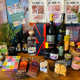 The Ultimate Hampshire & Dorset Hamper shown in display format - Hattingley Valley Classic Reserve English sparkling wine, B58 red, Danebury Madeleine Angevine white, 820 Spirits London Dry Gin and two Downton Brewery ales with Real Cure charcuterie, Chococo chocolates, Olives et Al oils, olives and preserves and the 24 inch lidded willow basket