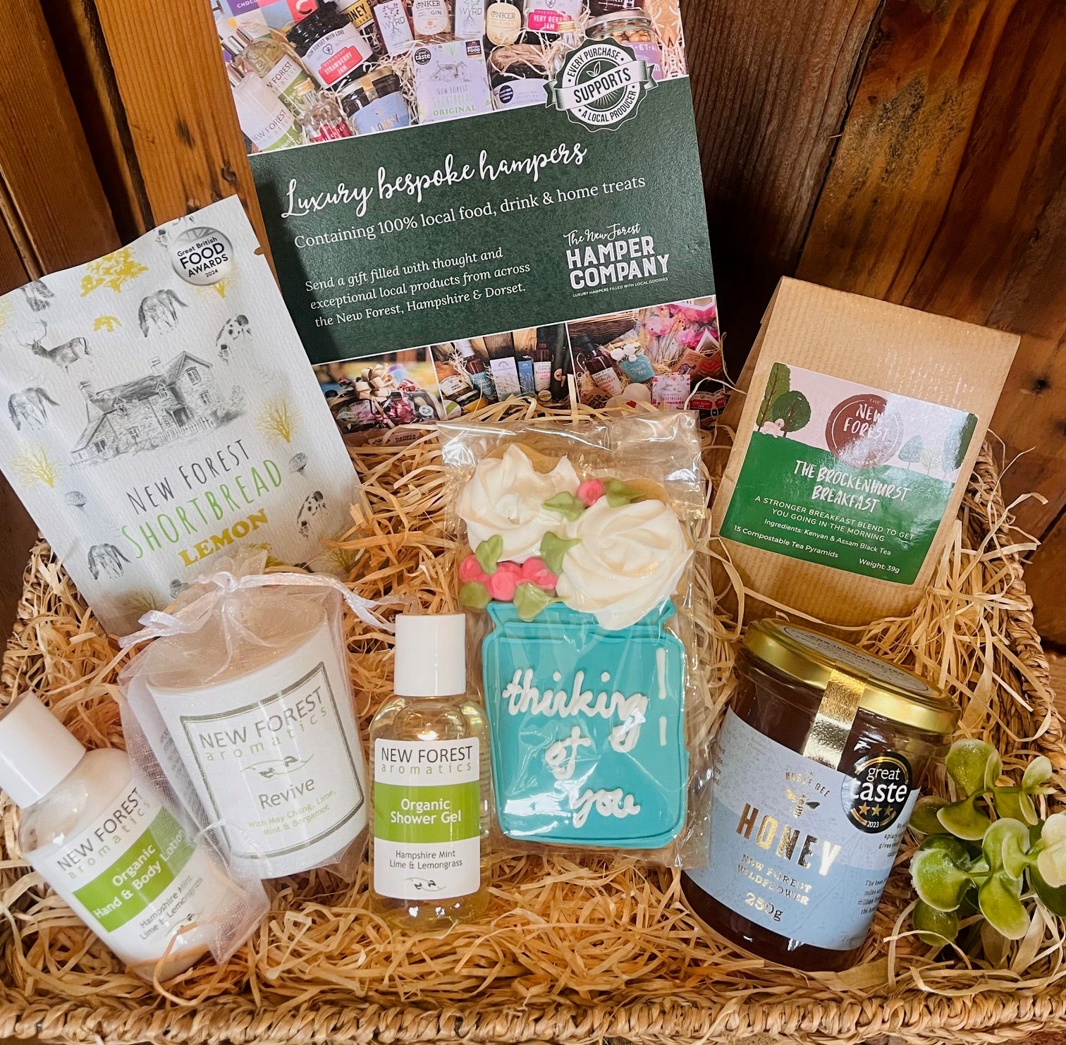 Uplifting Moments Hamper with New Forest Aromatics body care, Revive candle, New Forest tea, New Forest Shortbread, Noble Bee wildflower honey and a Little Bee Bakery hand-iced 'Thinking of You' biscuit.