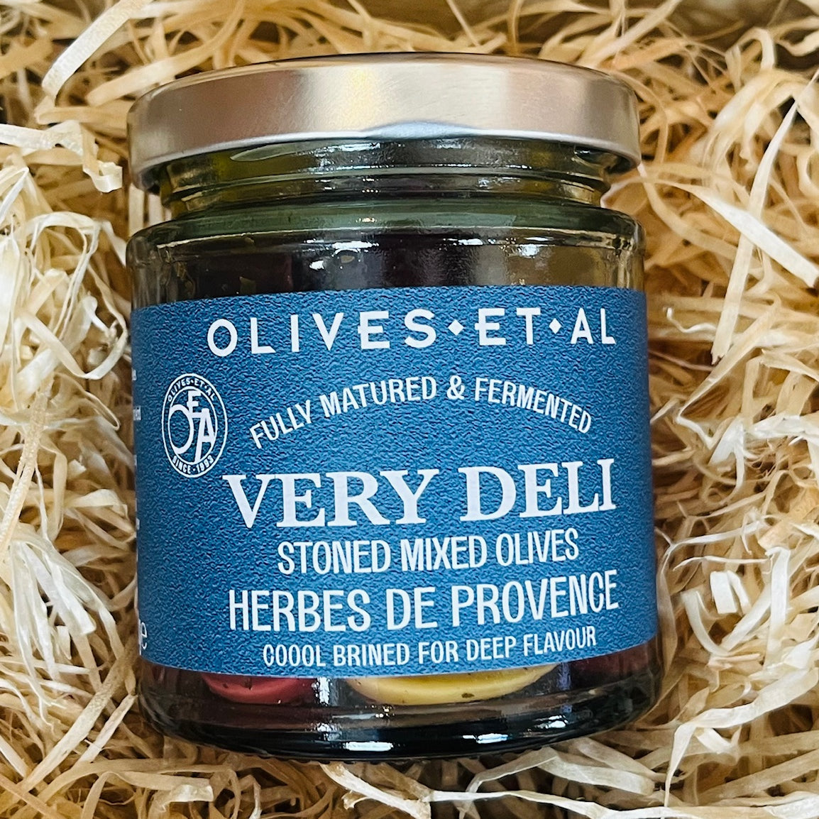 Jar of olives with a blue label on a bed of straw