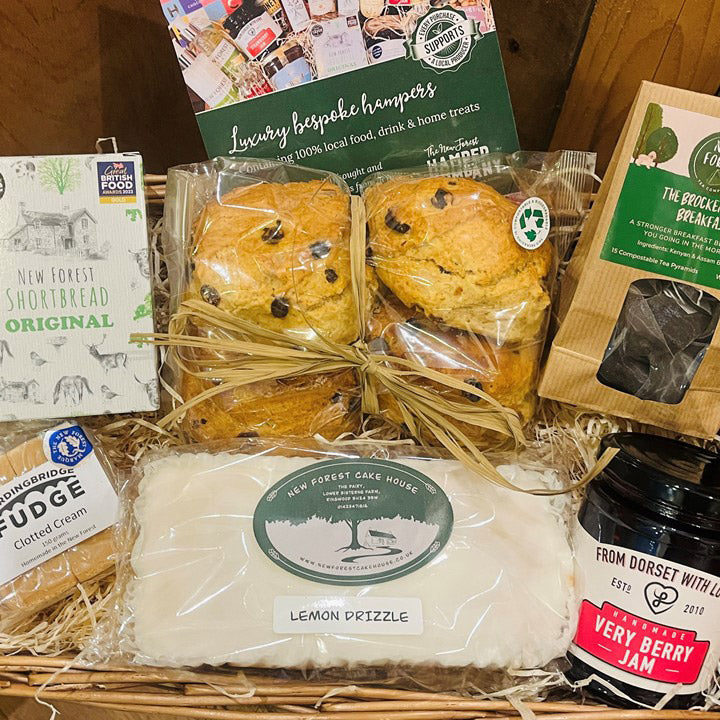 Gift basket with lemon drizzle cake, scones, and jam, featuring New Forest branding.