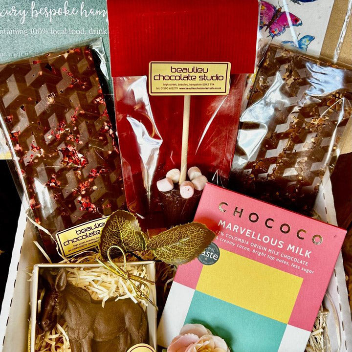 Assorted chocolate treats including a bar of chocolate with red berries, a chocolate-covered treat with marshmallows, and a pink box of CHOCOCO chocolate.