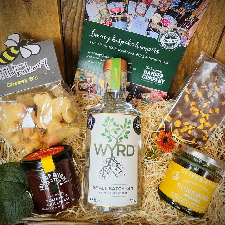 Gift hamper with Wyrd gin, snacks, and other items on a wooden background